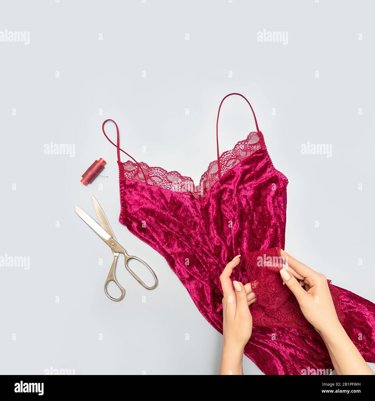 Il processo di cucitura manuale della biancheria. Forbici, accessori per cucire. Stringi nelle mani di un sarto da vicino. L'appartamento era sdraiato. Formato quadrato Foto Stock