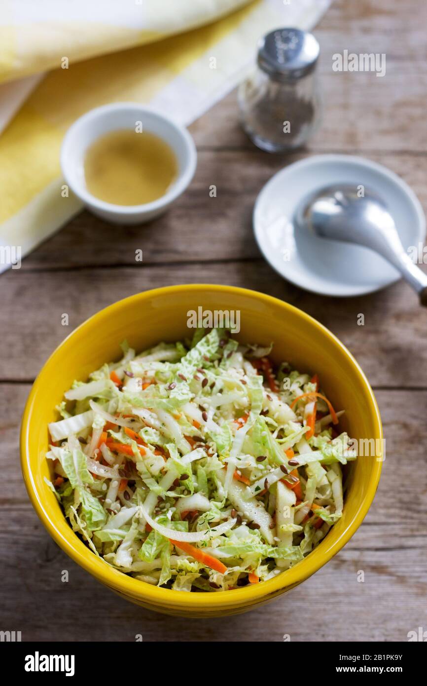 Coleslaw di cavolo, carote e varie erbe con la maionese in un piatto di grandi dimensioni su un sfondo di legno. Foto Stock