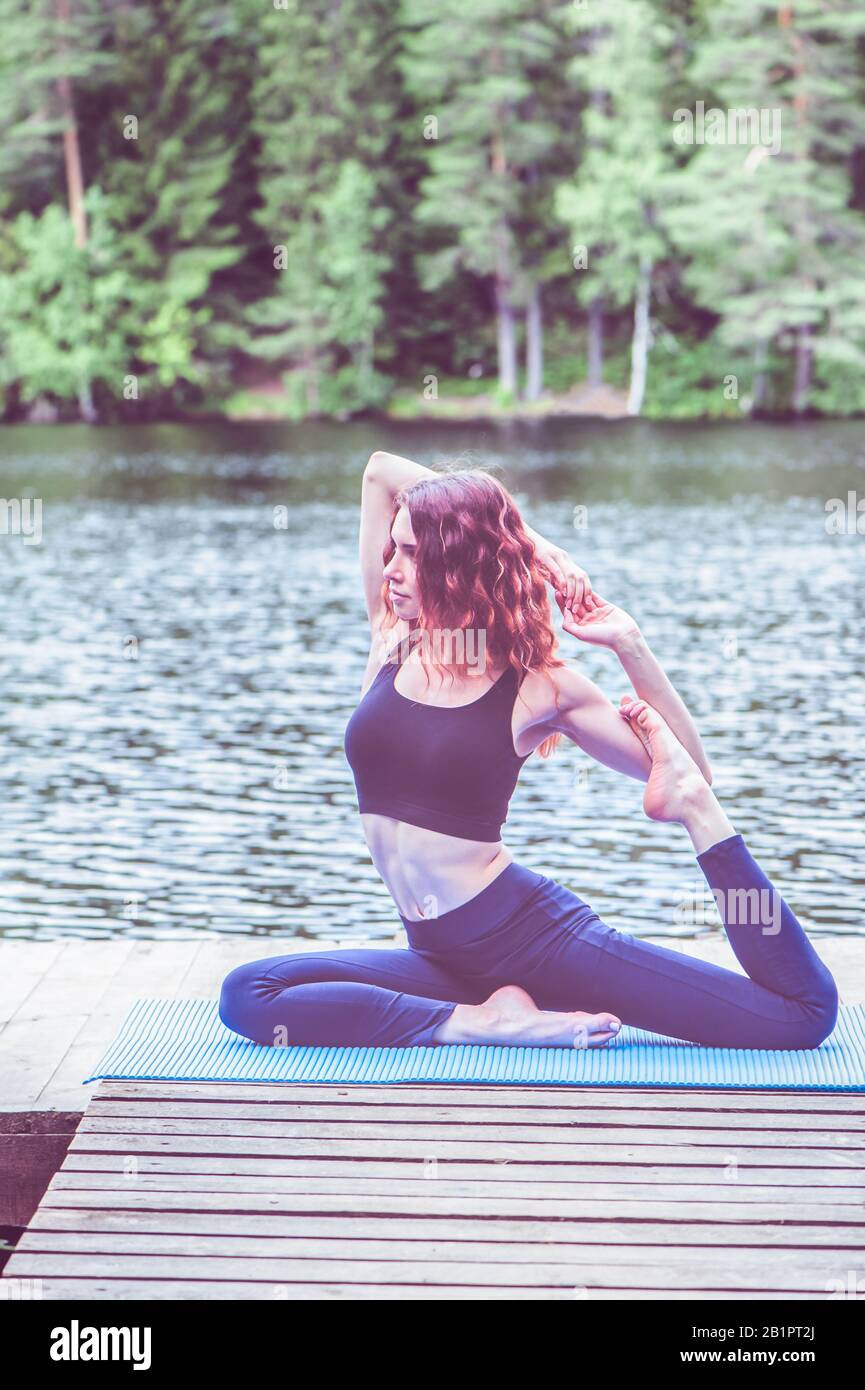 Bella ragazza in una posa yoga sul lago. Eka Pada Rajakapotasana . Una Posa Di Piccione Del Re Del Leged. Il concetto di pacificazione, stile di vita sano. Foto Stock