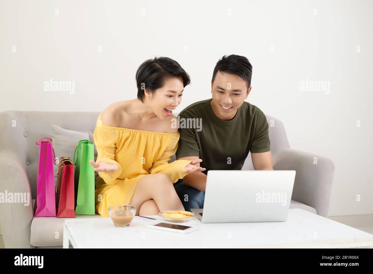 Emozionato Asian giovane utilizzando laptop per l'acquisto online con un buon affare. Foto Stock