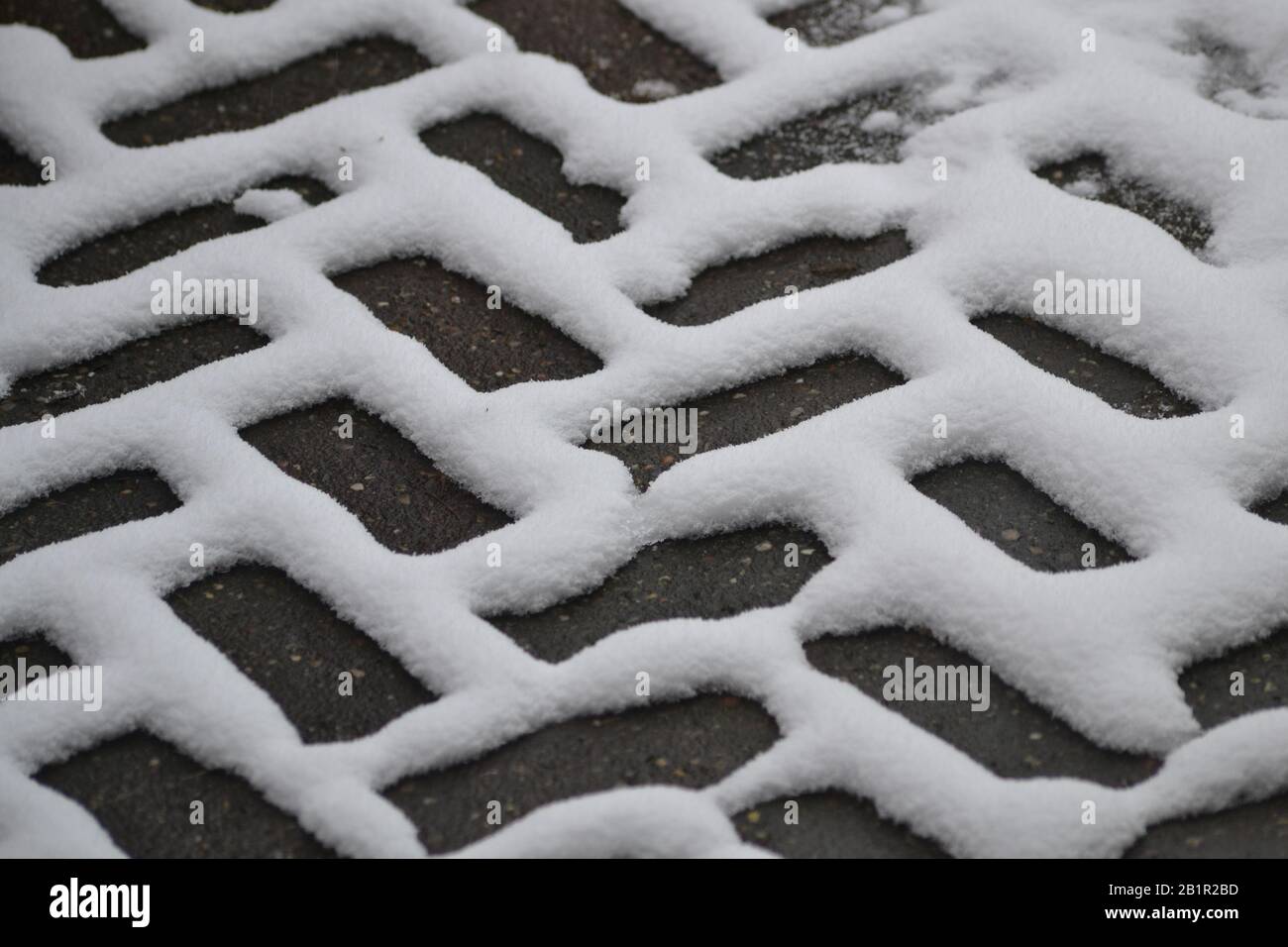 Neve che forma un motivo a spina di pesce sulla pavimentazione del blocco Foto Stock
