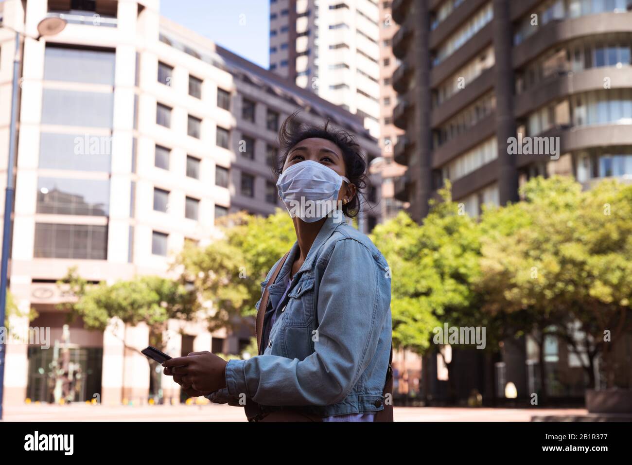 Donna che indossa una maschera Corona Virus e che usa il suo telefono Foto Stock