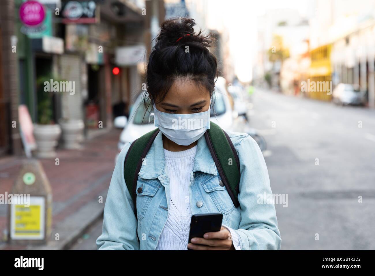 Donna che cammina per la strada e indossa una maschera Corona Virus Foto Stock