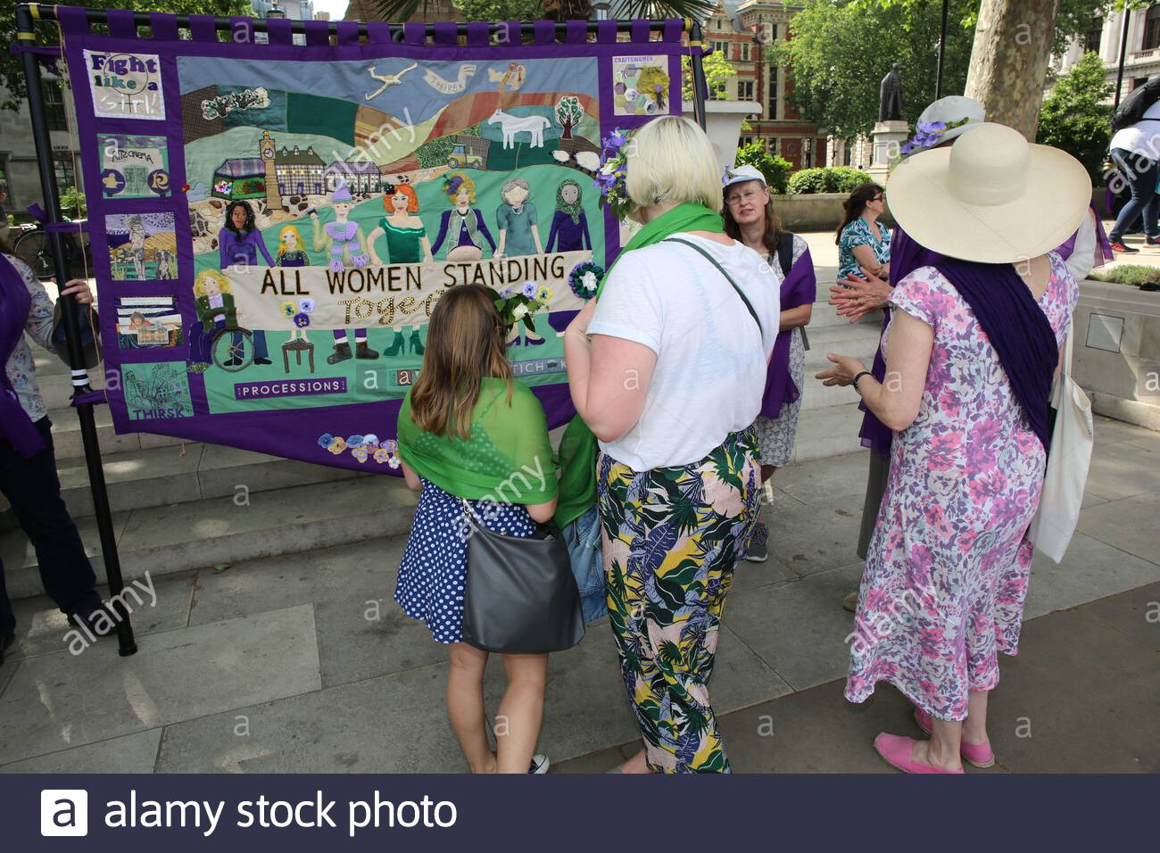 Le donne si riuniscono intorno ad un banner fatto per la sfilata di 100 anniversario che celebra il suffragio delle donne Foto Stock