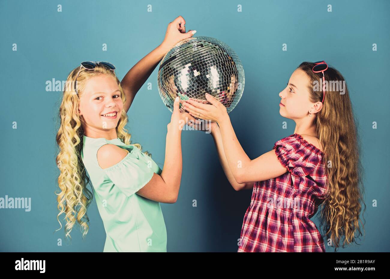 Musica retrò. Gli specchi riflettenti discoteca luci di atmosfera. Holiday celebrazione. Concetto di intrattenimento. Sorelle amici con palla da discoteca. Iniziare a parte. Allegro kids tenere palla da discoteca. Discoteca danze. Foto Stock