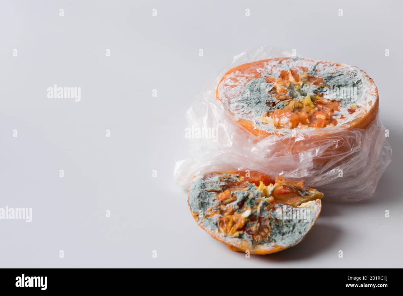 Ugly stampo arancione in cellophane pacchetto su grigio. Primo piano. Conservazione impropria della frutta. Foto Stock