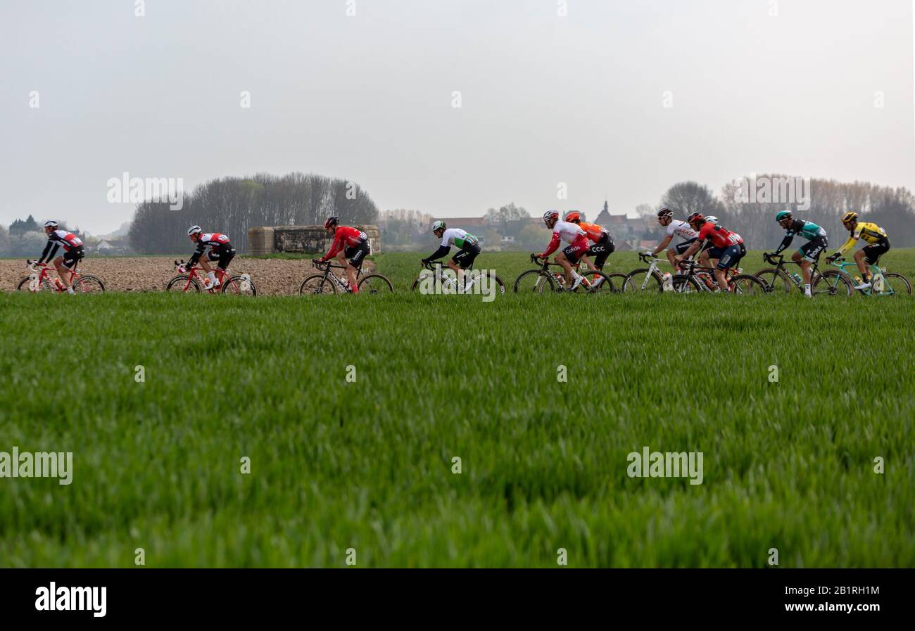 Viesly, Francia - 14 aprile 2019: Il peloton che guida sulla strada acciottolata polverosa da Cysoing a Bourghelles durante Parigi Roubaix 2019. Foto Stock