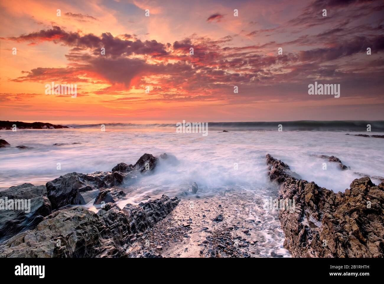 La marea in arrivo che arriva sopra le rocce Jurassic come, con il sole che tramonta su Hartland Quay, North Devon, South West, Hartland Peninsula, UK Foto Stock