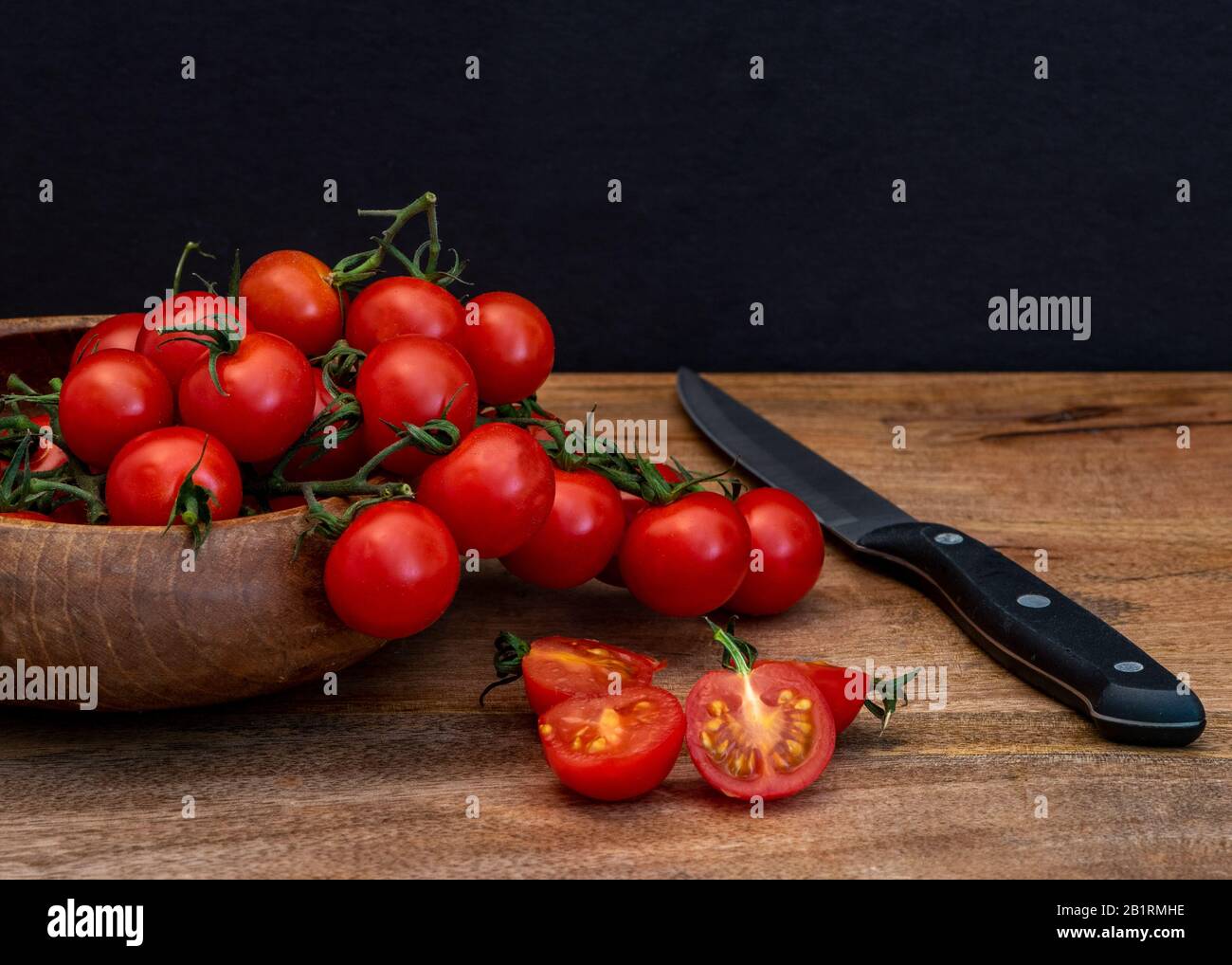 Fresco tomatillos su sfondo nero visto dal lato, Fresco intero e tagliato (dimezzato) rosso tomatillos su sfondo nero visto dall'alto - food st Foto Stock