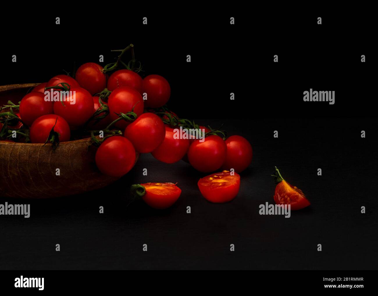 Fresco tomatillos su sfondo nero visto dal lato, Fresco intero e tagliato (dimezzato) rosso tomatillos su sfondo nero visto dall'alto - food st Foto Stock