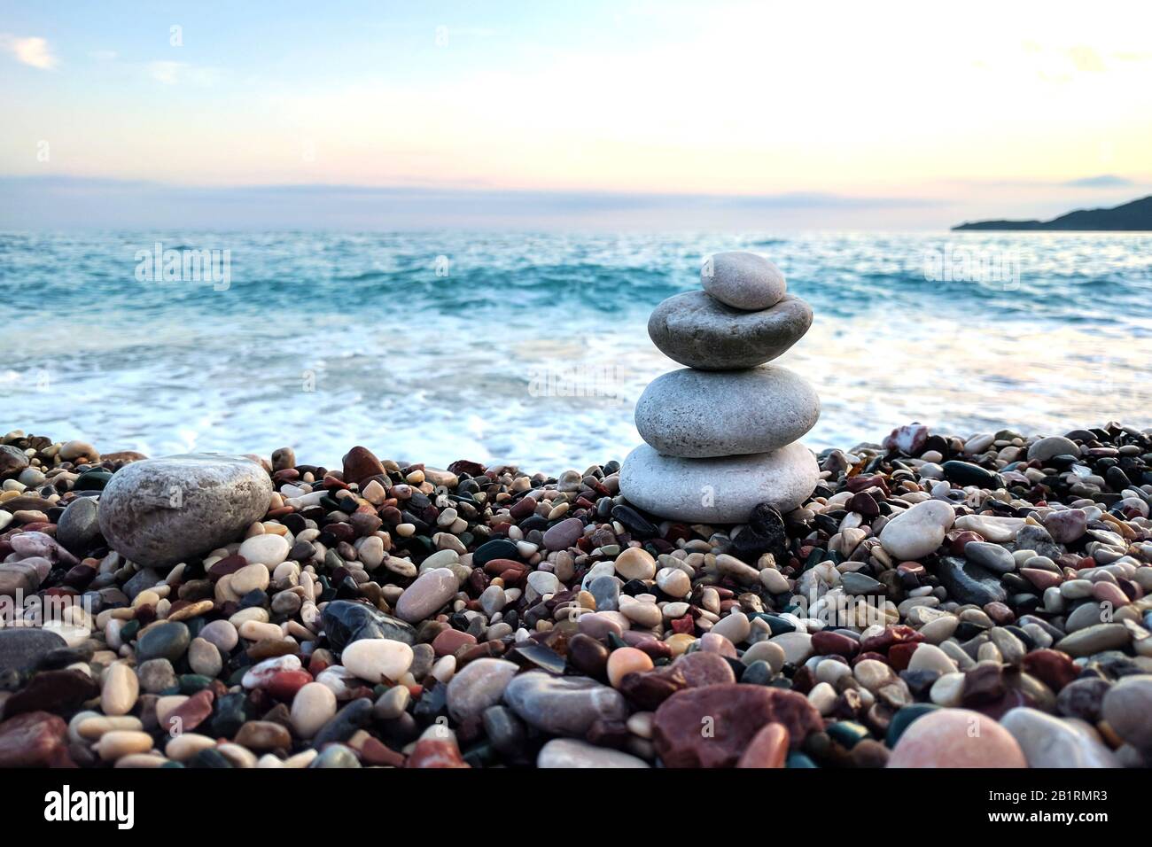 Pietre equilibrate vicino alla spiaggia. Tramonto sul mare. Foto Stock