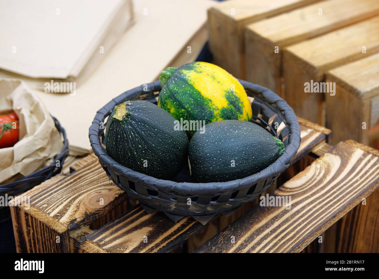 Zucchine rotonde verdi in vimini piatto su sfondo di legno. Foto Stock