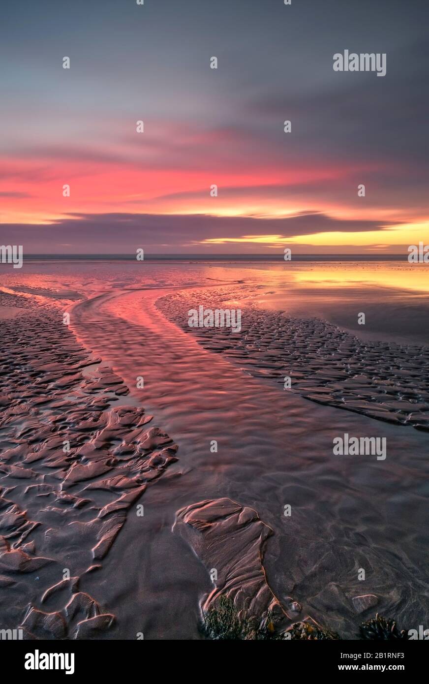 Spettacolare tramonto costiero sulla sabbia modellata, orizzonte cielo atmosferico, spiaggia, vita costiera, romantico, sera, cielo drammatico e luminoso, costa Foto Stock