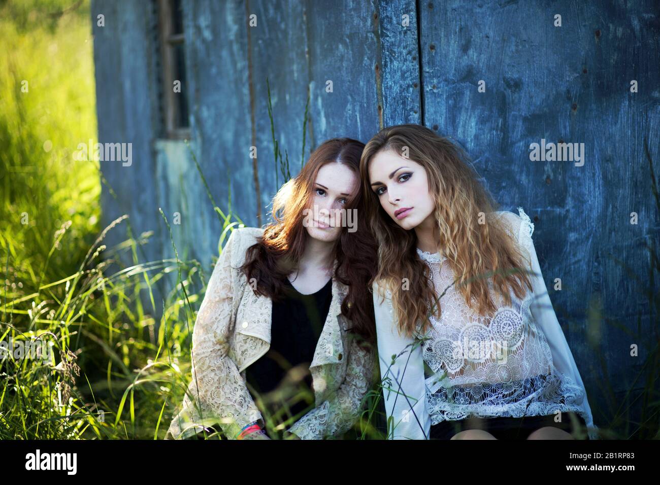 Due donne sono appoggiate contro un muro, Foto Stock