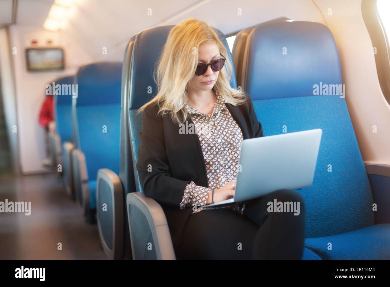 Bella donna che viaggia con un computer portatile in treno. Businesswoman che lavora sul computer durante i viaggi per lavoro Foto Stock