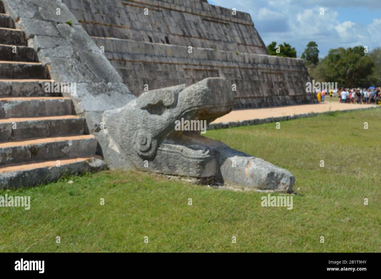 Una testa di serpente in pietra scolpita si trova alla base della scalinata di El Castillo, il tempio di Kukulcan, nell'antico sito archeologico maya di Chich Foto Stock