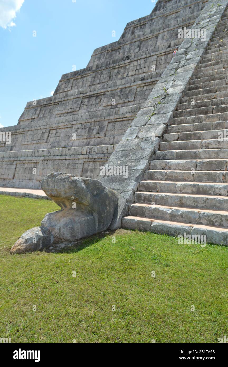 Una testa di serpente in pietra scolpita si trova alla base della scalinata di El Castillo, il tempio di Kukulcan, nell'antico sito archeologico maya di Chich Foto Stock