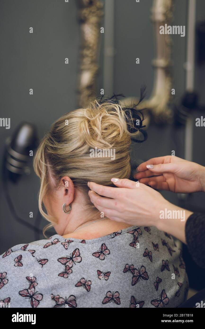 le mani di uno stilista o parrucchiere che styling i capelli della donna in un salone dei capelli Foto Stock