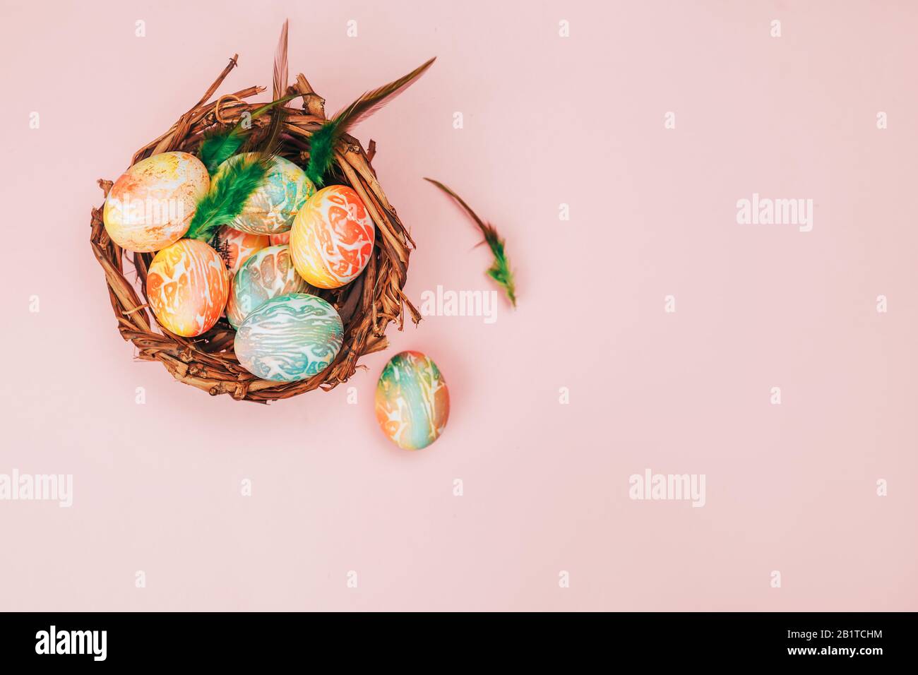 Colofy uova di pasqua in nido su sfondo color rosa pastello, copia spazio. Foto Stock