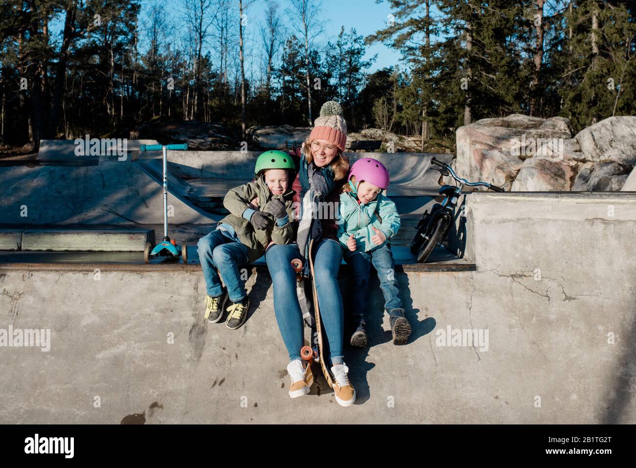 mamma che gioca con i suoi bambini in uno skatepark all'aperto divertirsi Foto Stock