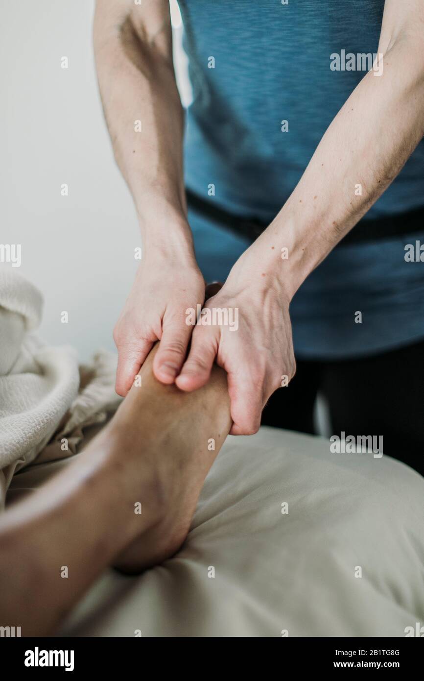 la terapista femminile usa le mani per massaggiare il piede del cliente Foto Stock