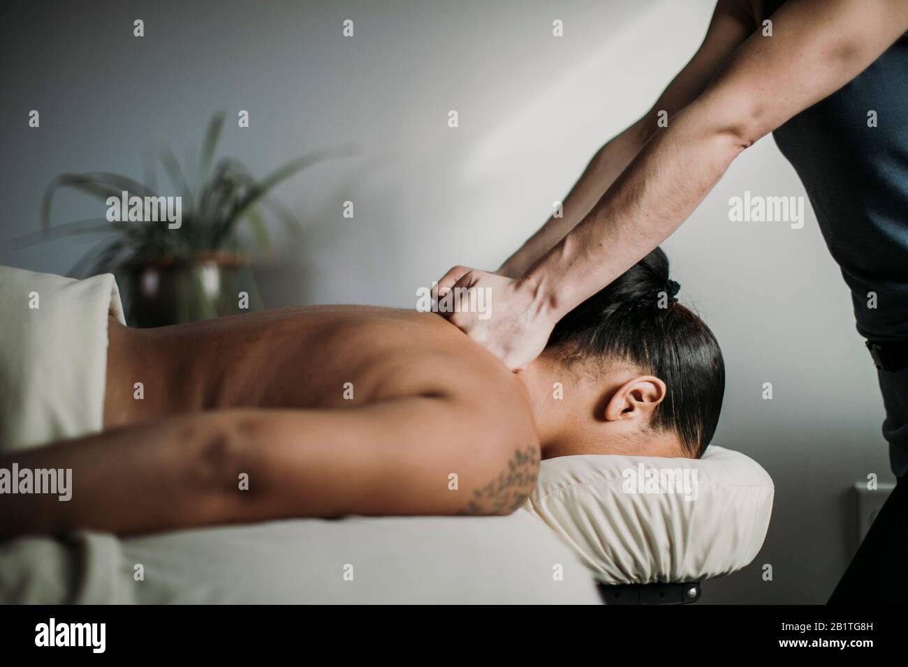 il terapista dei massaggi usa il pugno per trattare le spalle dei clienti afro-americani Foto Stock