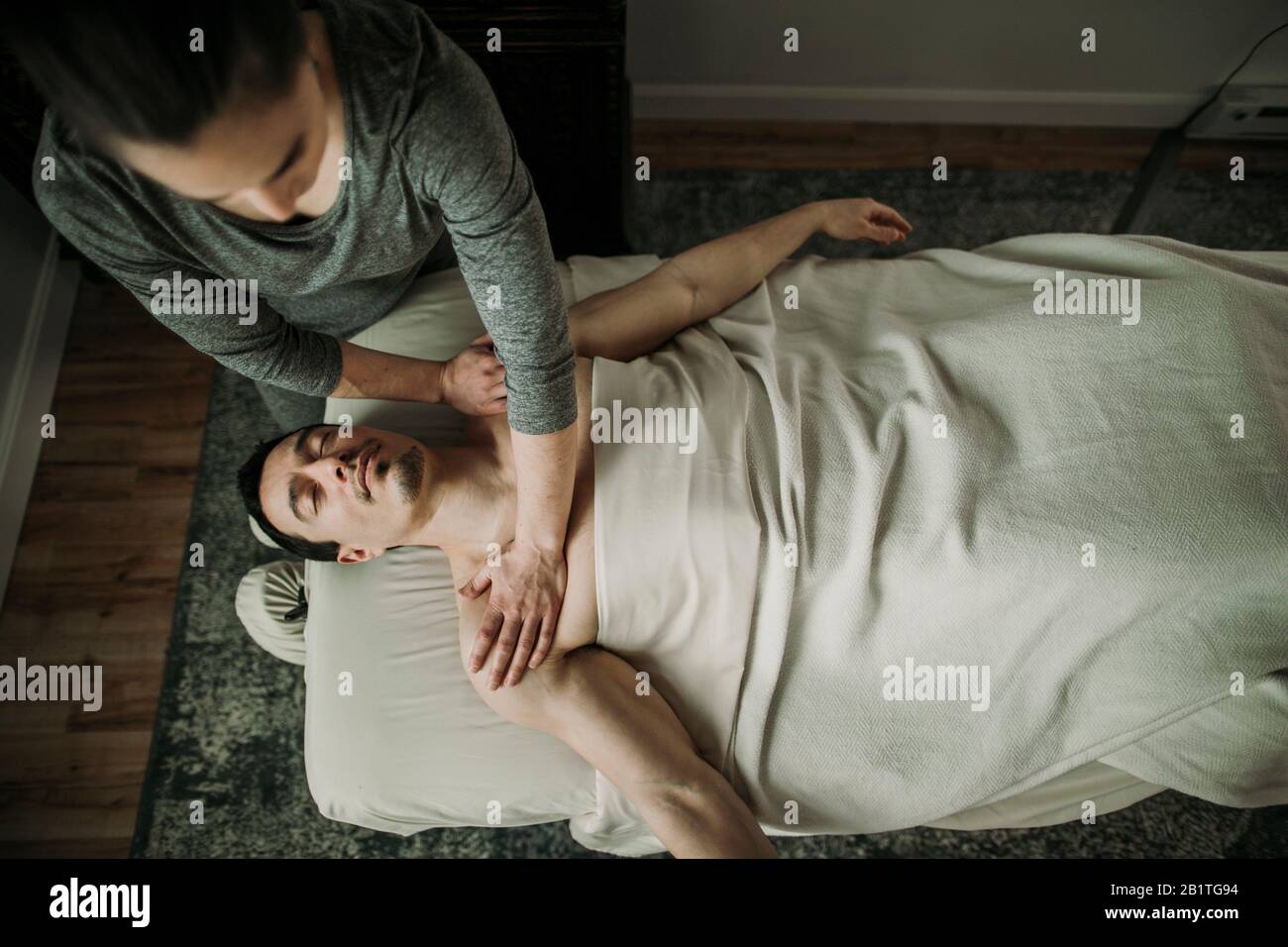 La terapista del massaggio femminile applica pressione alle spalle del maschio Foto Stock