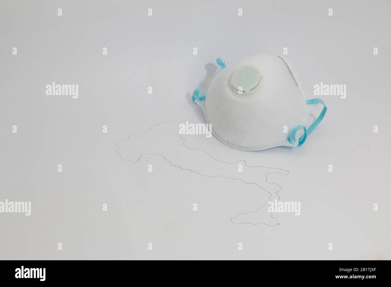 Freiburg, GERMANIA - 24 FEBBRAIO 2020: Una maschera medica di tipo FFP2 accanto ad una mappa simbolica dell'italia che rappresenta lo scoppio del nuovo virus corona / SARS Foto Stock
