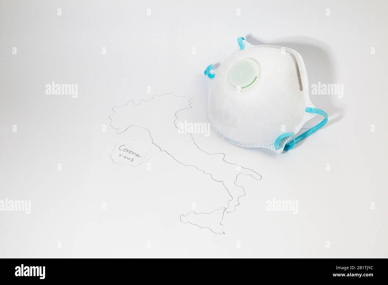 Freiburg, GERMANIA - 24 FEBBRAIO 2020: Una maschera medica di tipo FFP2 accanto ad una mappa simbolica dell'italia che rappresenta lo scoppio del nuovo virus corona / SARS Foto Stock