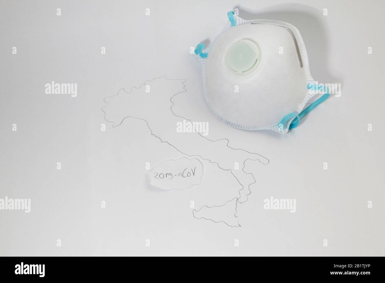 Freiburg, GERMANIA - 24 FEBBRAIO 2020: Una maschera medica di tipo FFP2 accanto ad una mappa simbolica dell'italia che rappresenta lo scoppio del nuovo virus corona / SARS Foto Stock