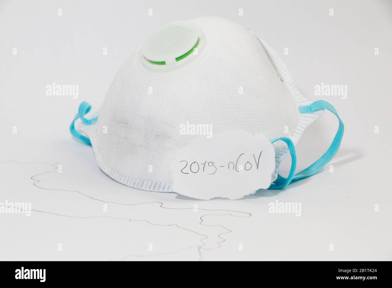 Freiburg, GERMANIA - 24 FEBBRAIO 2020: Una maschera medica di tipo FFP2 accanto ad una mappa simbolica dell'italia che rappresenta lo scoppio del nuovo virus corona / SARS Foto Stock