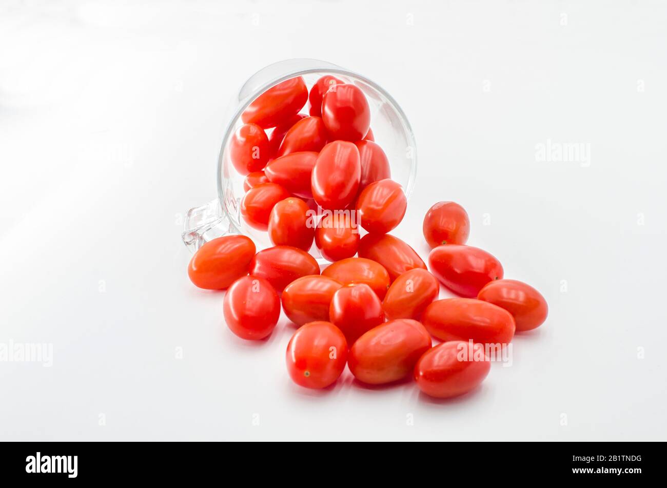 Pomodori ciliegini (mini) nella tazza di vetro. Ciliegia o mini pomodori in vetro isolato su sfondo bianco Foto Stock