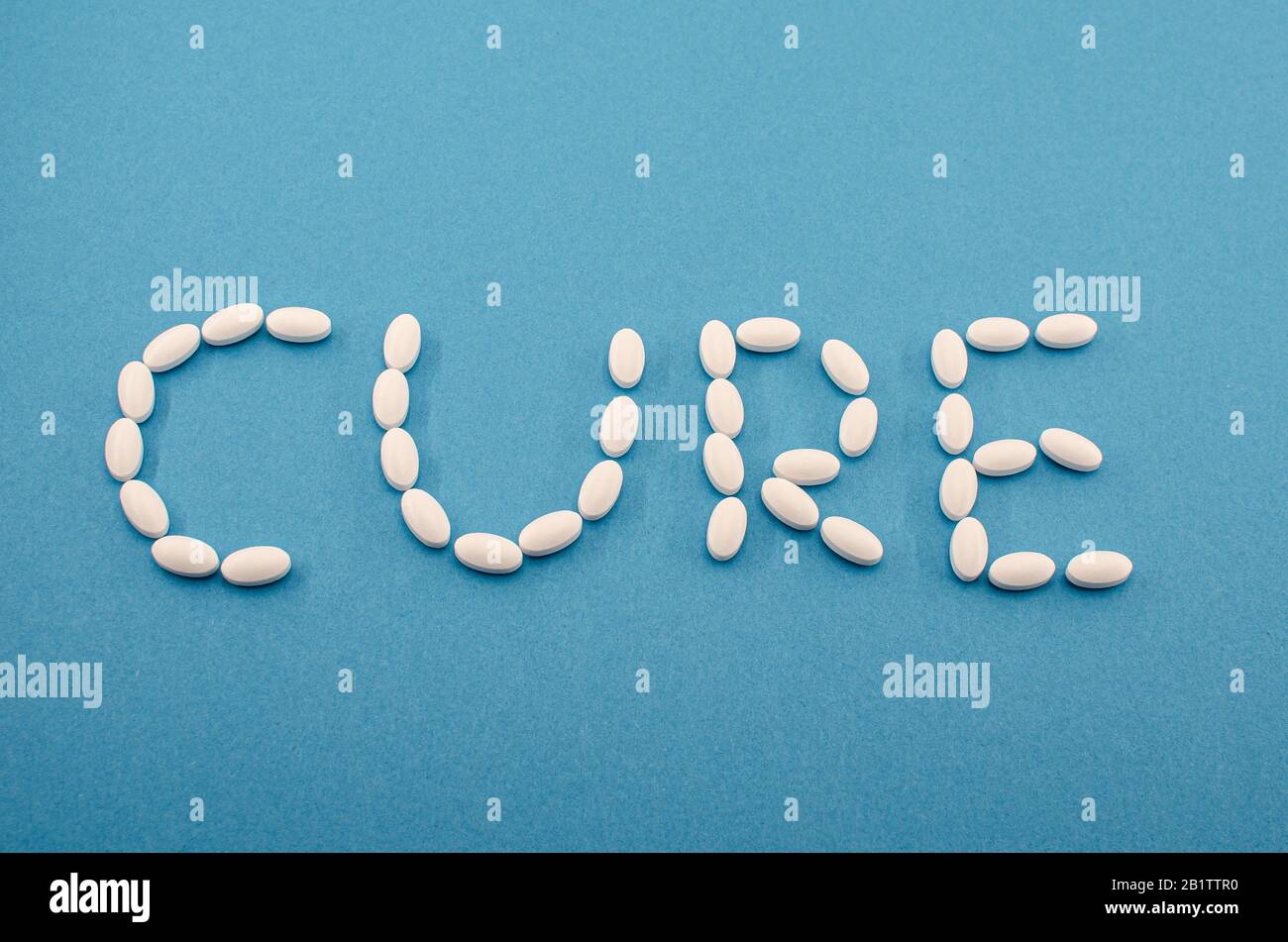 Pillole bianche mediche, compresse che formano la parola cura su sfondo blu. Medicina, farmaci trattamento delle malattie. Concetto di un nuovo coronavirus cinese Foto Stock