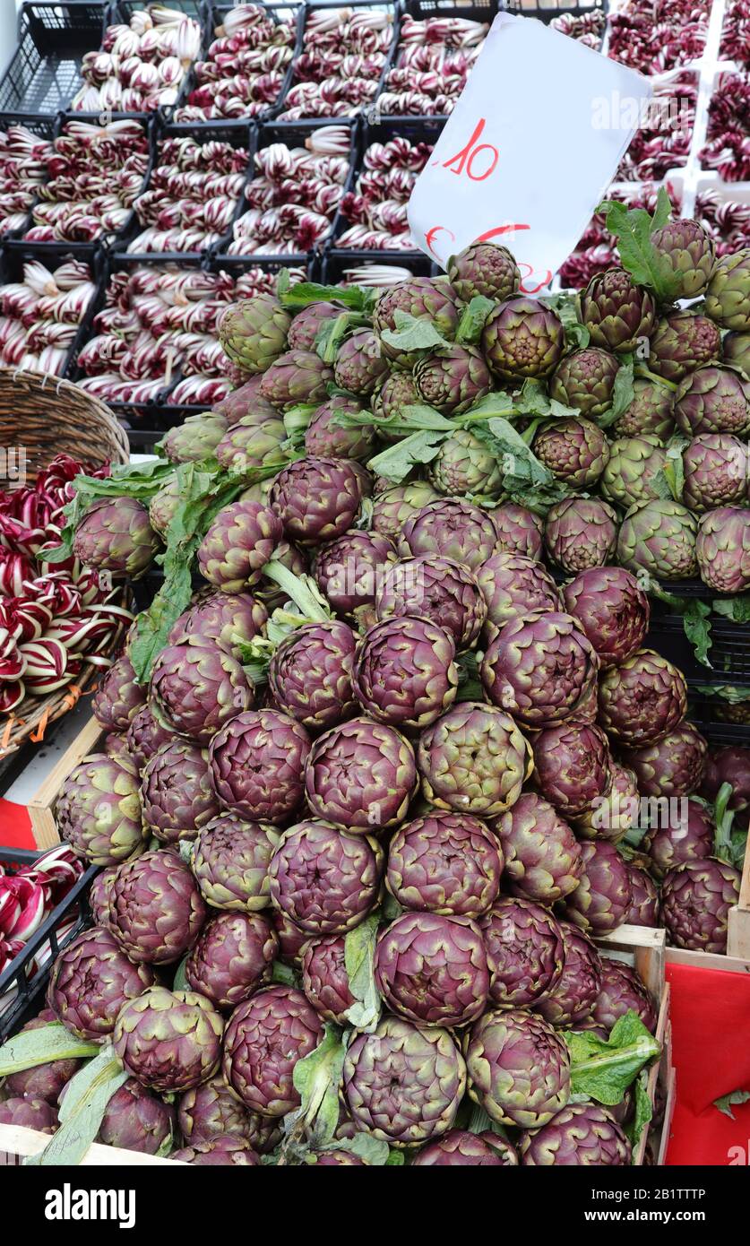 Stalla fruttivendolo con scatole complete di verdure e CARCIOFI in vendita sul mercato locale Foto Stock