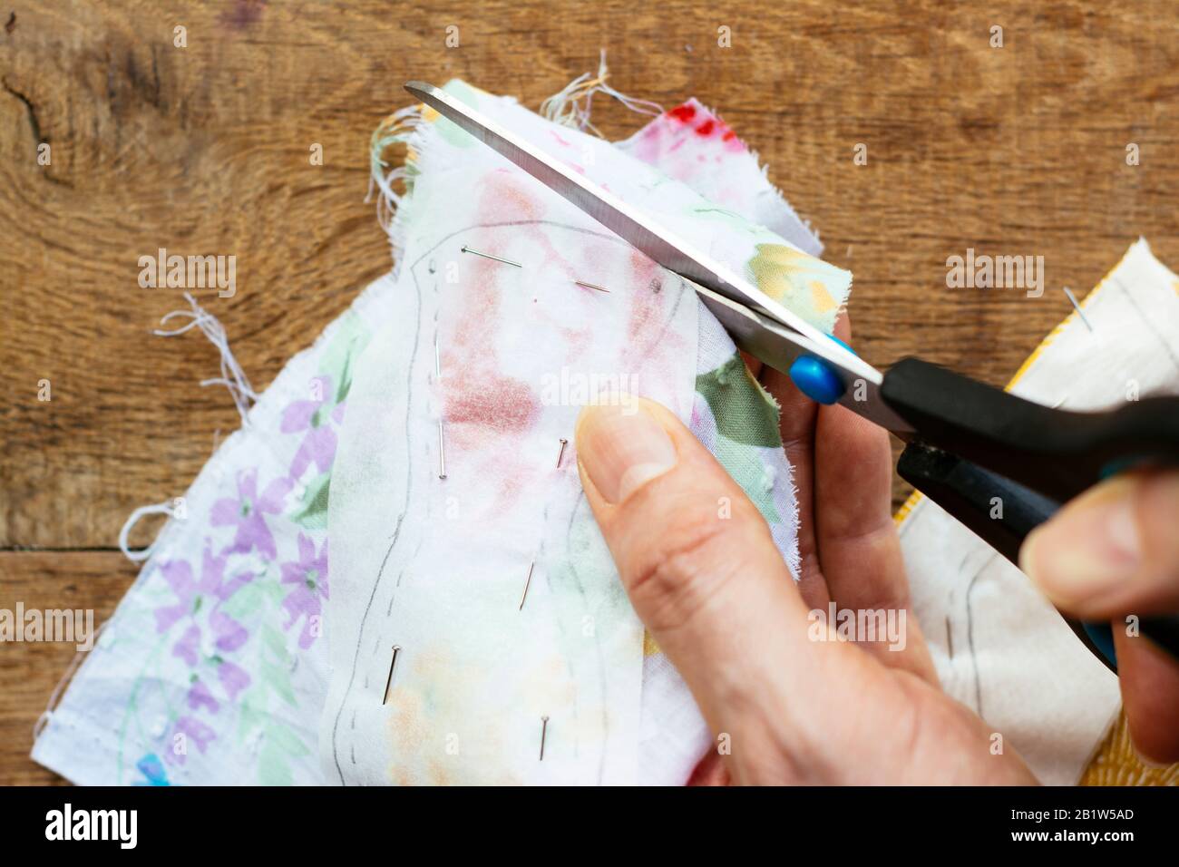 Taglio di un modello di cucito a forma di uccello da un tessuto del pezzo con le forbici. Foto Stock