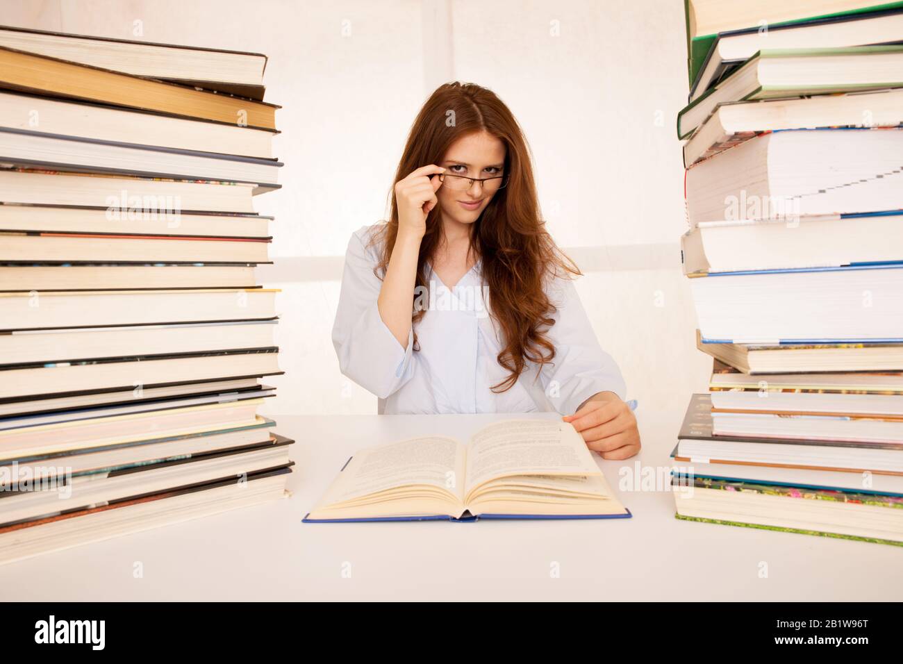 attraente giovane donna studia wtih hugr libro mucchi sulla sua scrivania Foto Stock