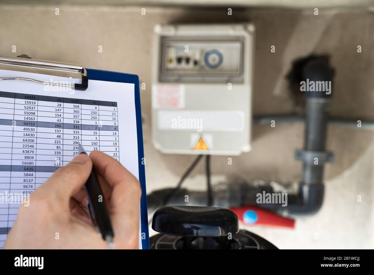 Appunti Di Worker Holding Ispezione Della Pompa Dell'Acqua E Dei Tubi Foto Stock