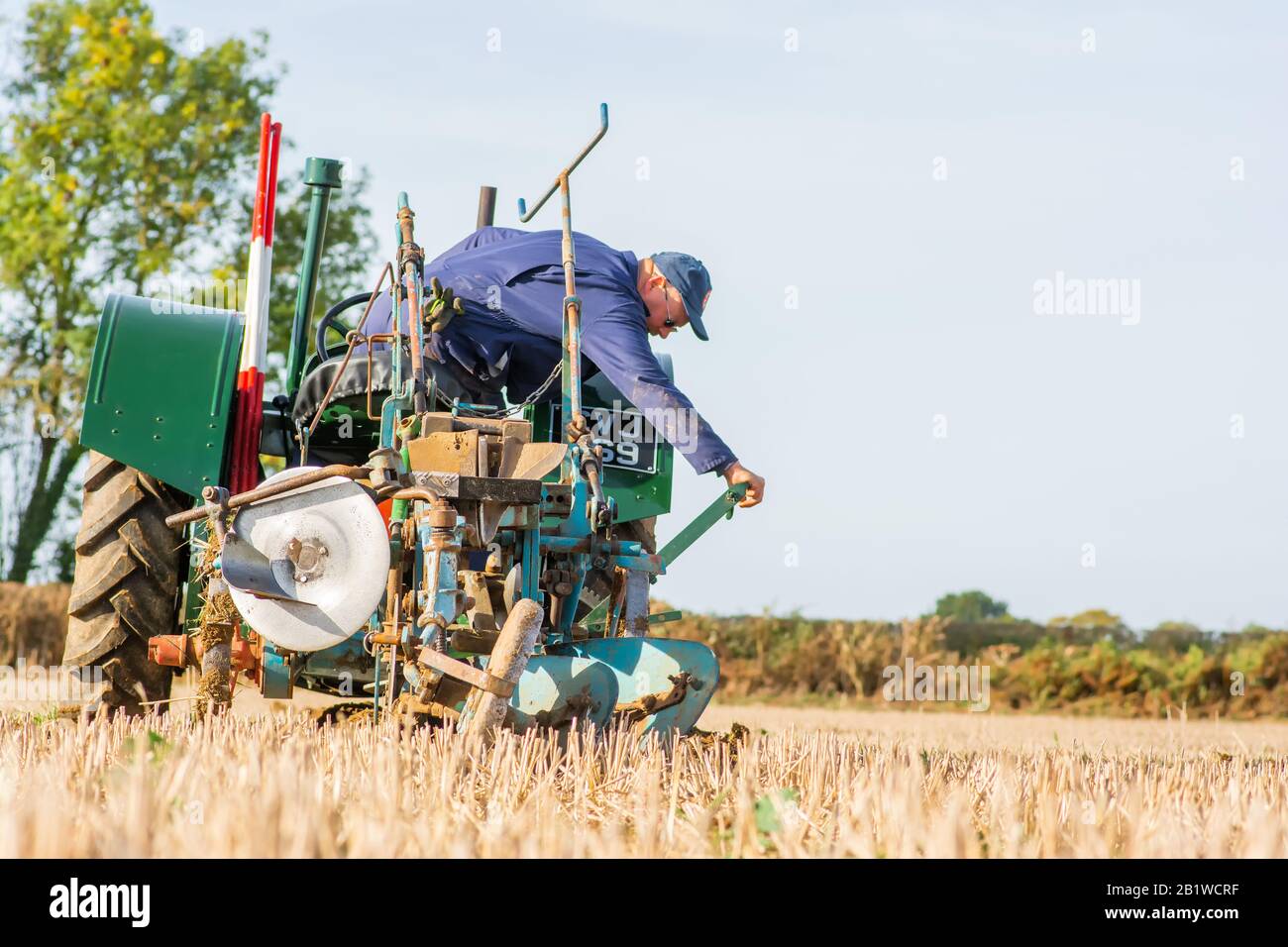 Piccolo trattore verde vintage contadino plowig il solco in un campo in fattoria nel Berkshire Inghilterra 2018 Foto Stock