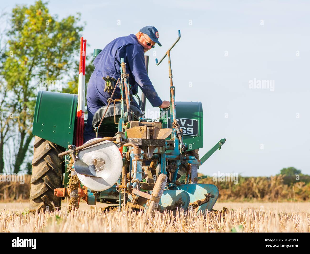 Piccolo trattore verde vintage contadino plowig il solco in un campo in fattoria nel Berkshire Inghilterra 2018 Foto Stock