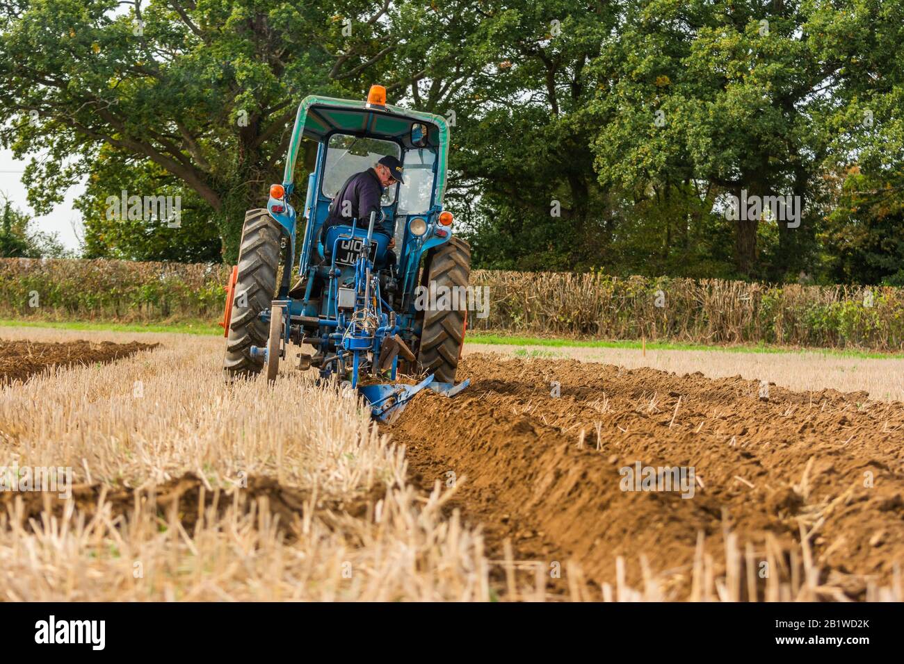 Blue Tractor con tetto verde vintage Farmer plowig il solco in un campo in azienda nel Berkshire Inghilterra 2018 Old Oxfordshire Foto Stock