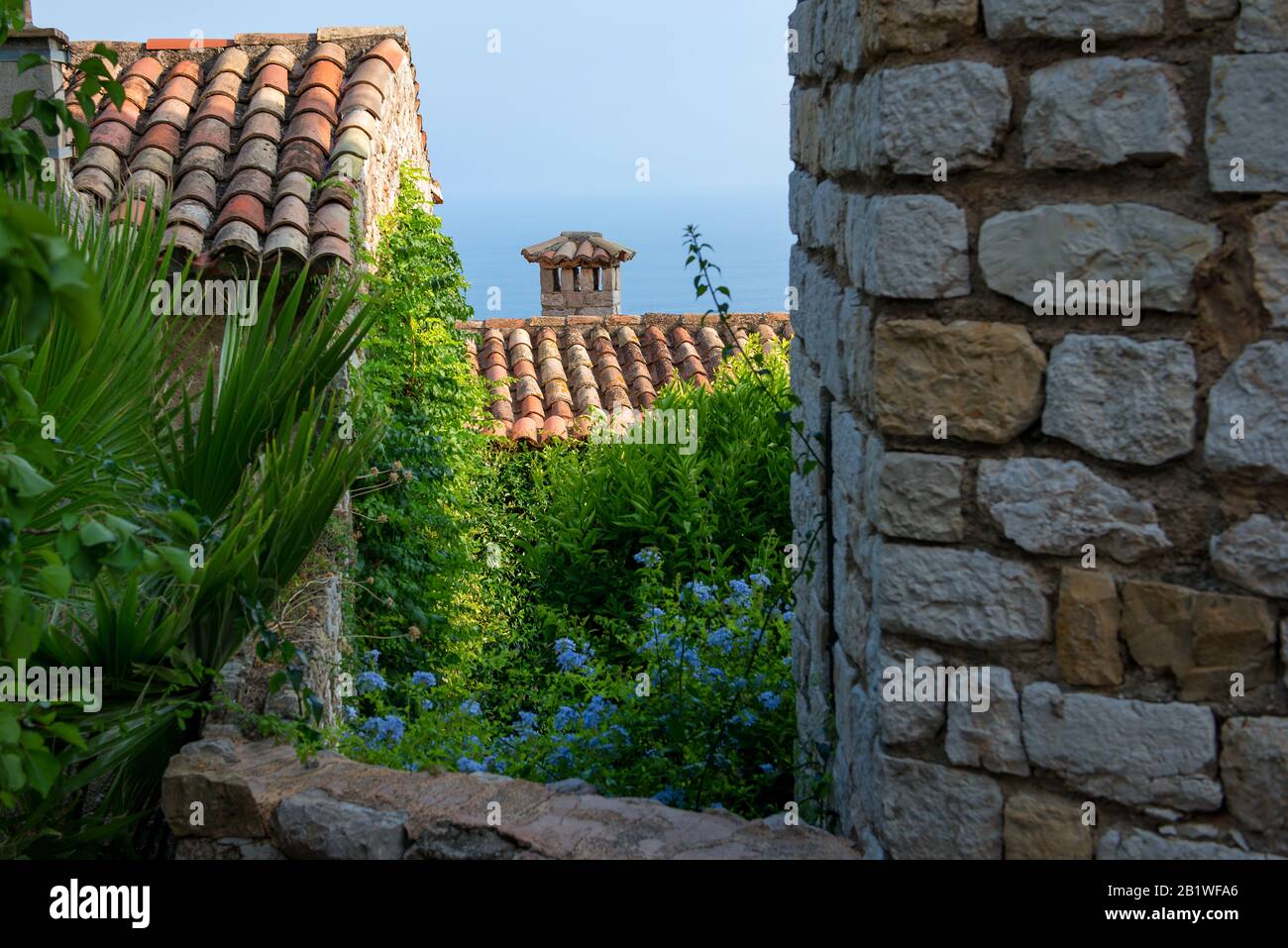 Côte d'Azur/Costa Azzurra: Vista sull'oceano attraverso i tetti storici dell'antico villaggio francese Foto Stock