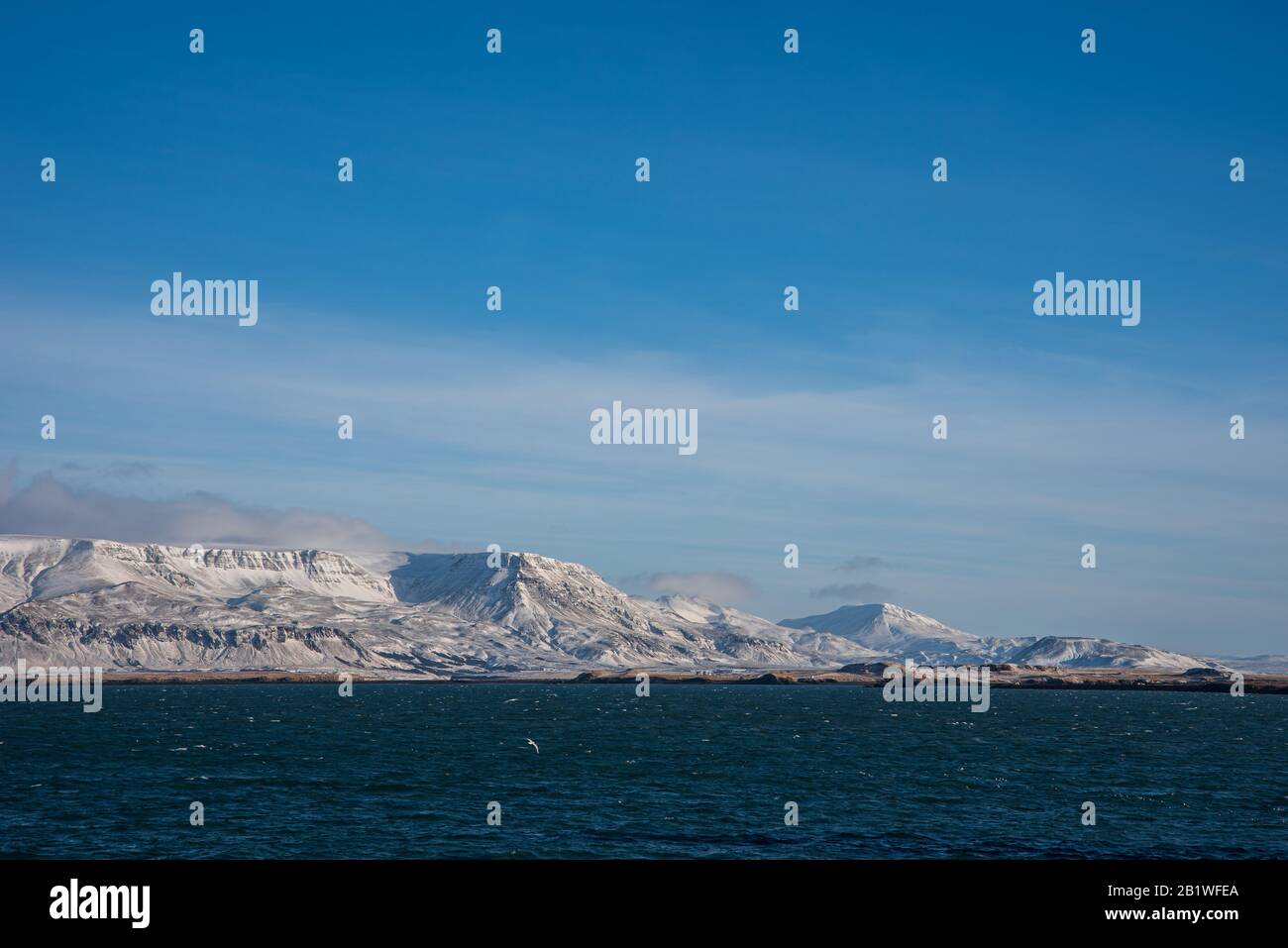 Linea di costo con montagne innevate in Islanda Foto Stock