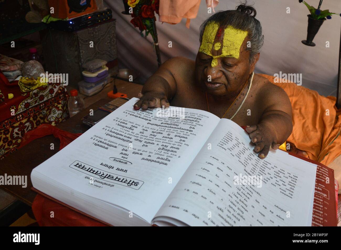 Jabalpur, India. 26th Feb, 2020. Shri Sant Raghav Das (vaman ji) Maharaj legge 'Ramcharit Manas' (libro sacro degli indù) da Avadh dham, Digambar akhada durante Narmada Kumbh in Jabalpur. Le braccia e le gambe sono sottosviluppate dalla nascita. (Foto Di Sanat Kumar Singh/Pacific Press) Credito: Pacific Press Agency/Alamy Live News Foto Stock