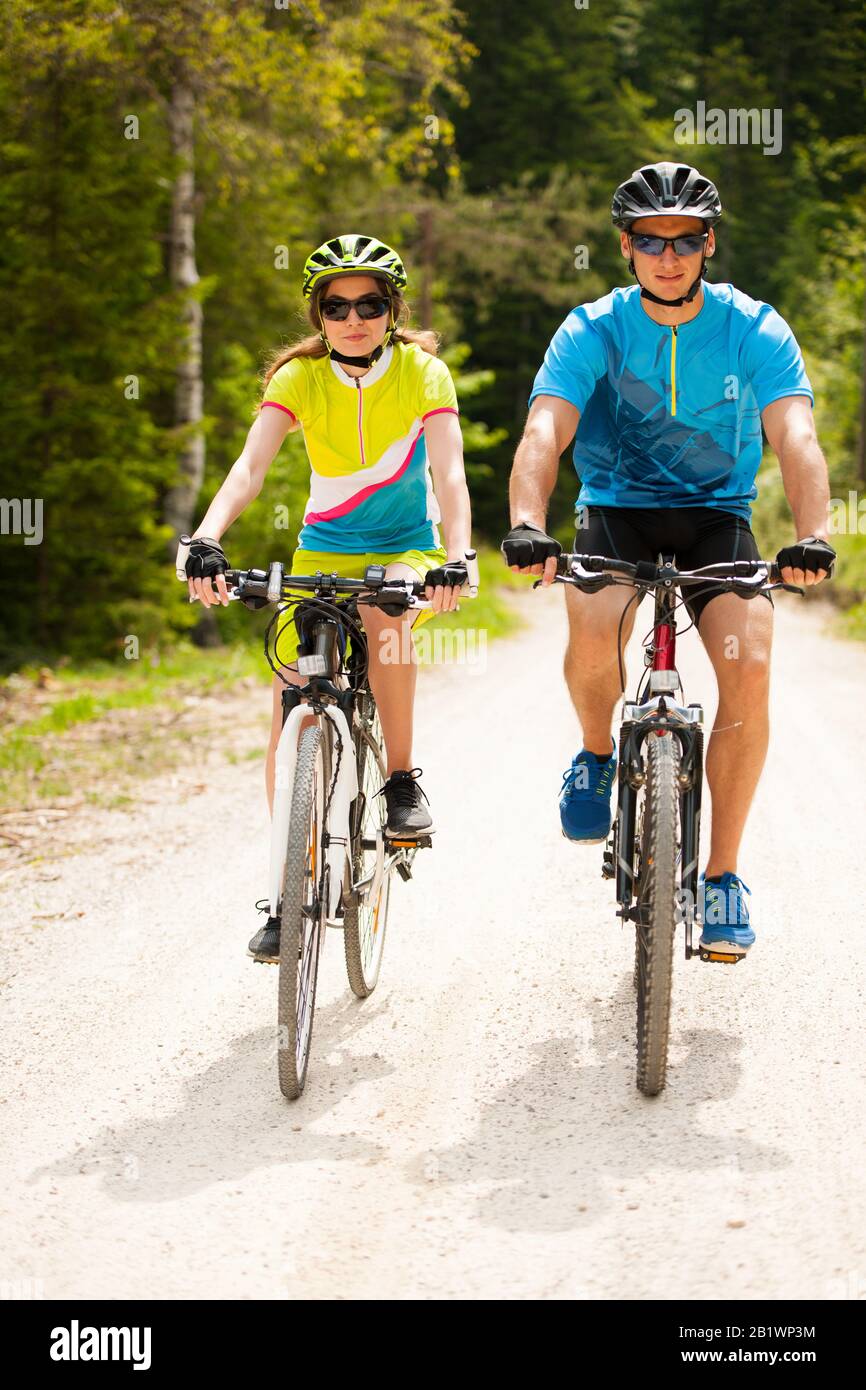 Attiva giovane coppia in bicicletta su una strada forestale in montagna in una giornata di primavera Foto Stock