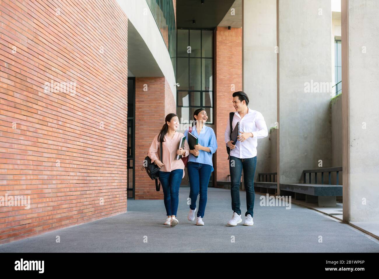 Asian tre studenti stanno camminando e parlando insieme nella sala universitaria durante la pausa in Università. Istruzione, Apprendimento, Studente, Campus, Università, Foto Stock