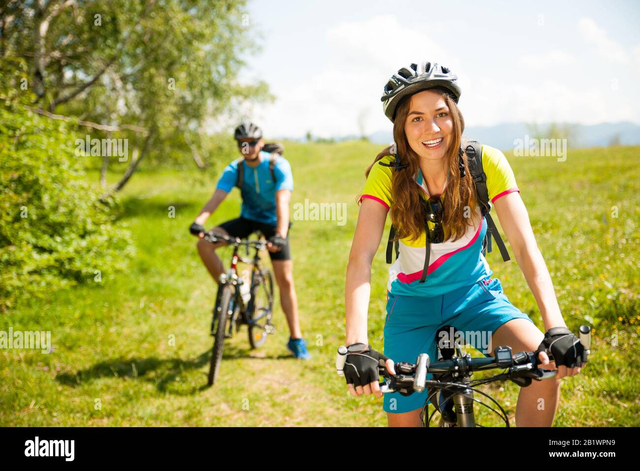 Attiva giovane coppia in bicicletta su una strada forestale in montagna in una giornata di primavera Foto Stock