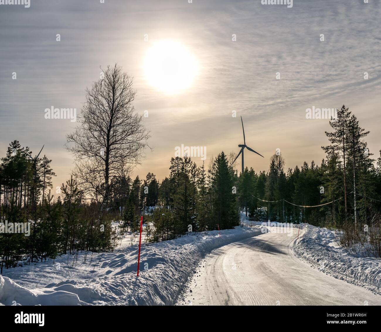 Foto di mulino a vento e strada curvy in inverno pineta foresta, cielo blu, nebbia inverno sole, Svezia, ambiente amichevole energia pulita Foto Stock