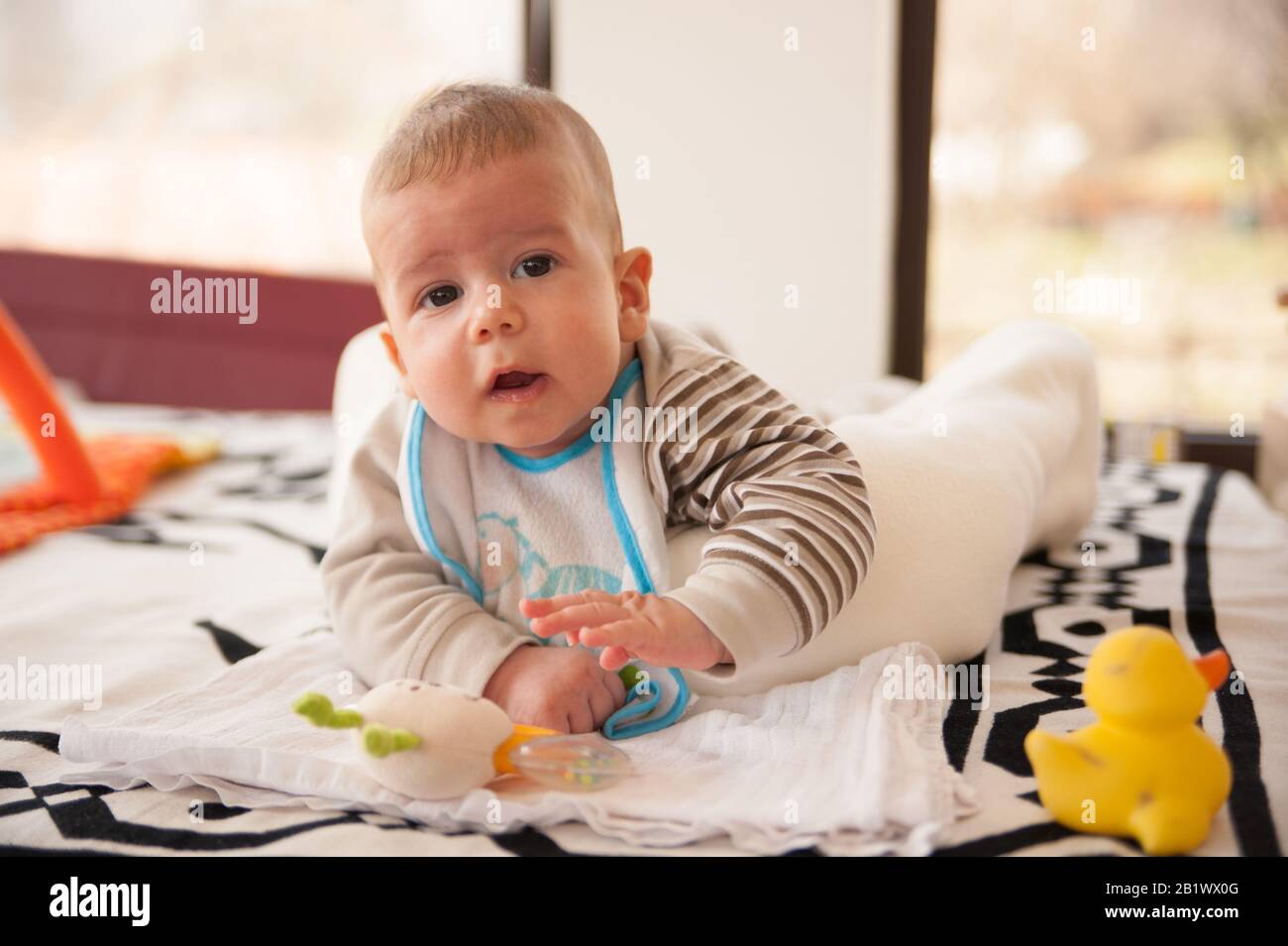 bambino di 3 mesi gioca con i suoi giocattoli e guarda la fotocamera Foto Stock