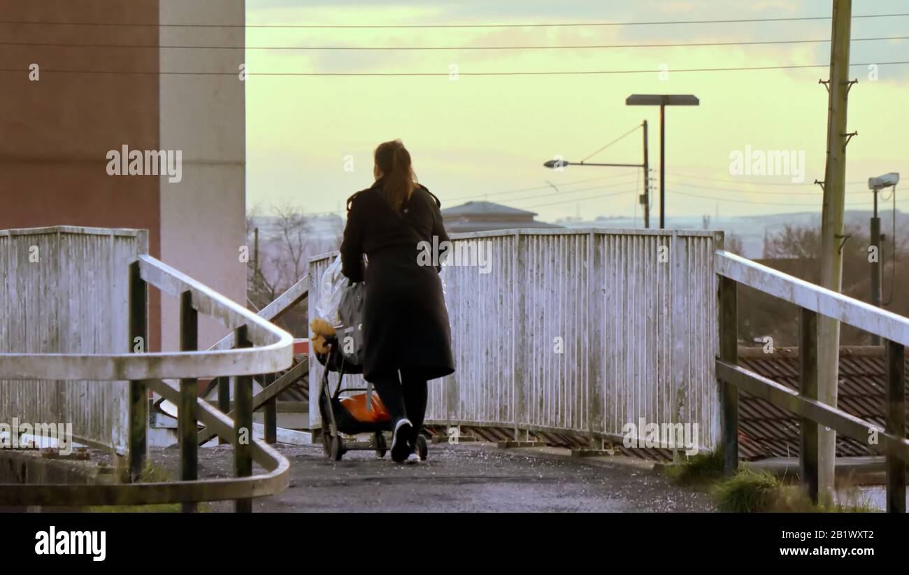 Madre singola che spinge il carrozzone camminando sul ponte del canale Forth e clyde a Glasgow Foto Stock