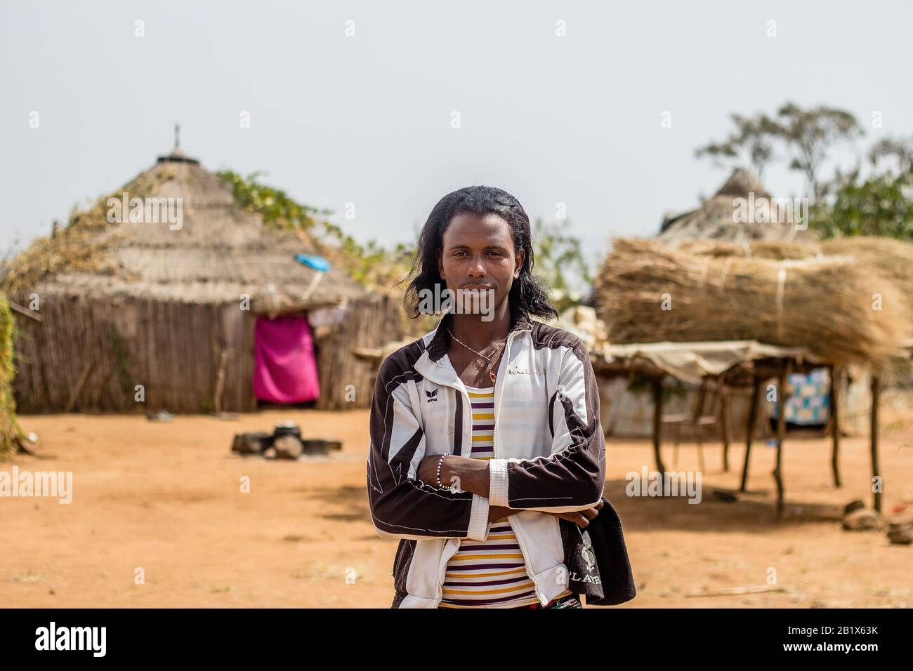 Un ragazzo di Hausa/Fulani posa per la foto di fronte a una casa di paglia in un villaggio di Abuja, Nigeria. Foto Stock